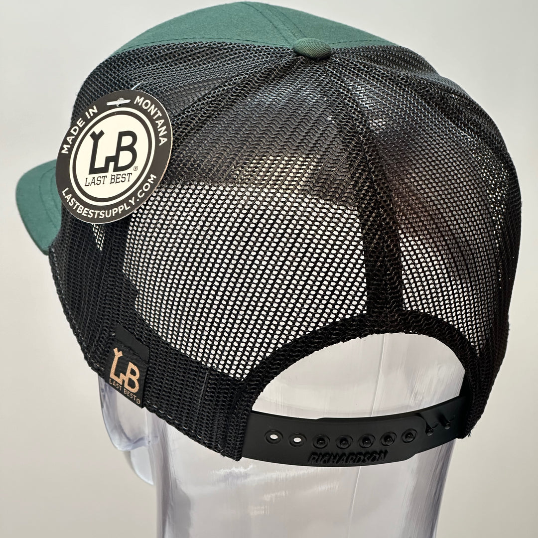 the back of a hand dyed leather patch hat with bigfoot's face sewn onto a green Richardson flat bill trucker hat with black mesh.