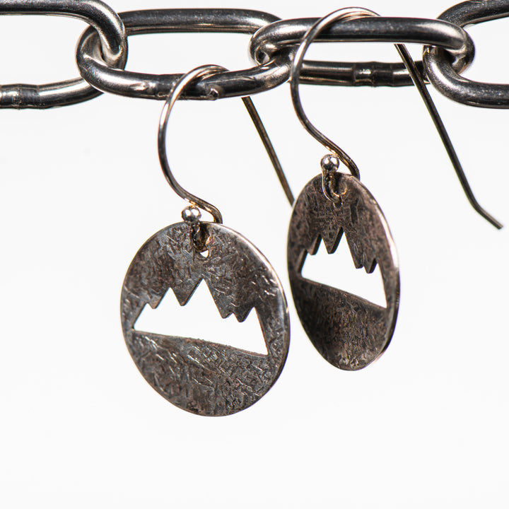 Cobblestone Design of Montana's Disc Earrings, handcrafted earrings featuring a textured sterling silver disc with a mountain-shaped cutout