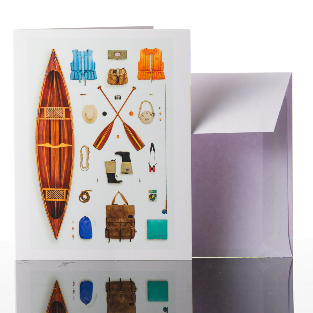 A 4.25" x 5.5" greeting card featuring a flat lay of a canoe and canoeist adventure gear.