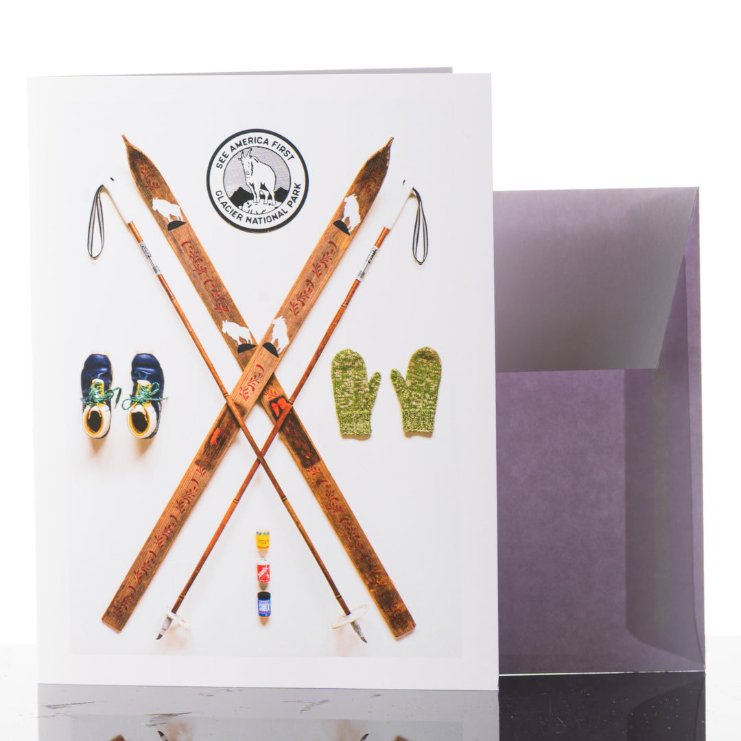 This greeting card features vintage wooden skis and a Glacier National Park stamp.