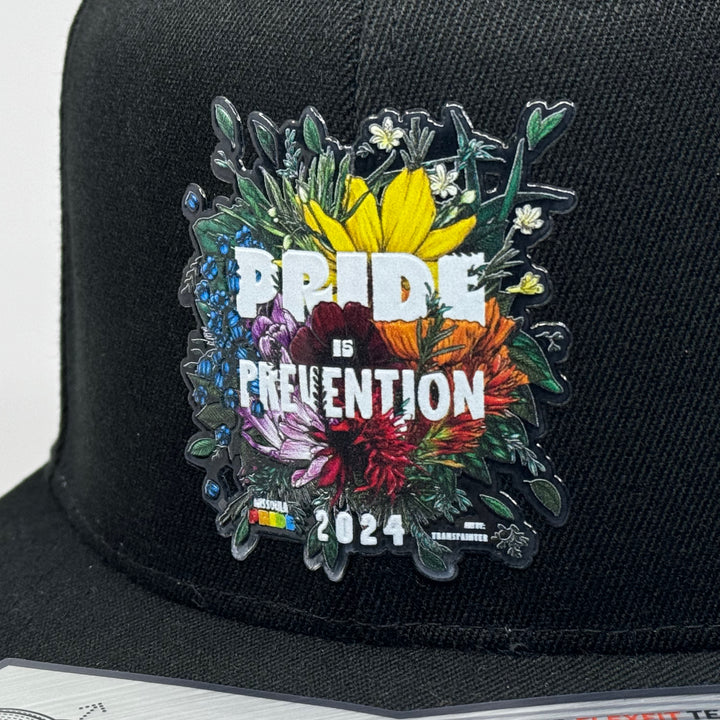 Black flat bill hat featuring the 2024 Missoula PRIDE design Pride is Prevention, closeup patch detail (3/4 view)