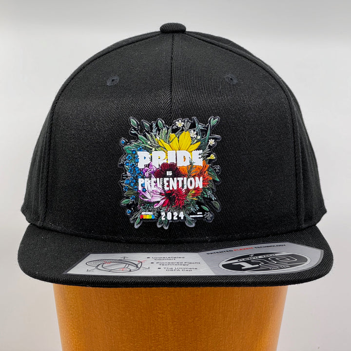 Black flat bill hat featuring the 2024 Missoula PRIDE design Pride is Prevention, front view