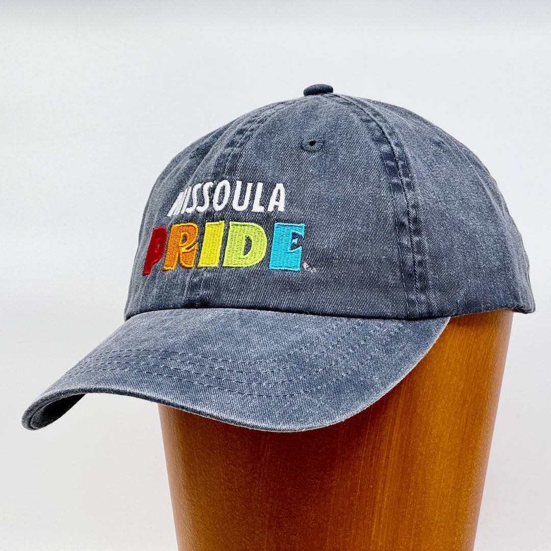 Charcoal grey pigment dyed unstructured hat featuring the Missoula PRIDE logo, 3/4 view