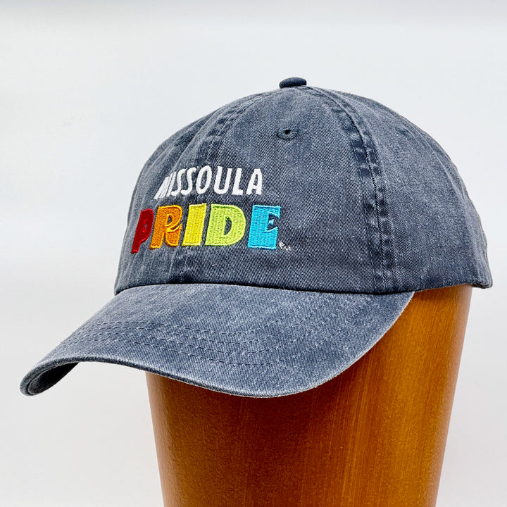 Charcoal grey pigment dyed unstructured hat featuring the Missoula PRIDE logo, 3/4 view