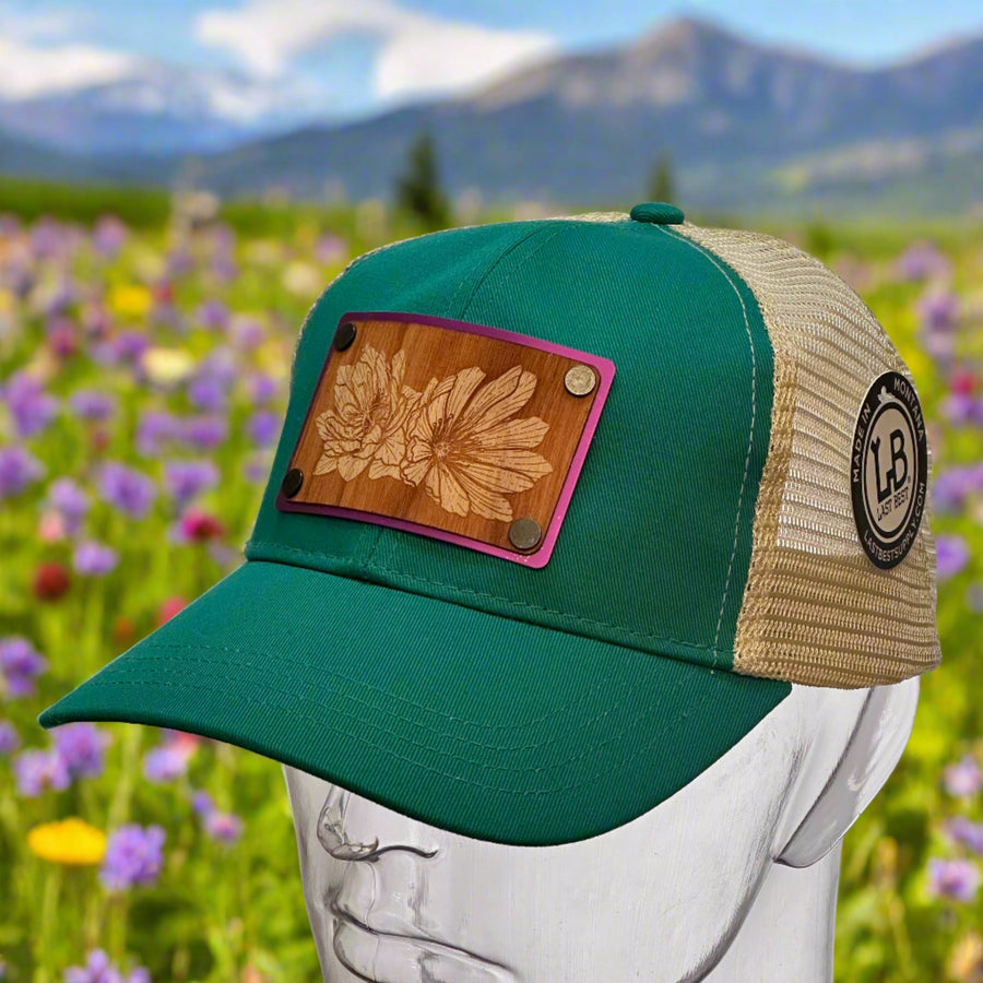 A wood and metal patch hat with an etching of a bitterroot flower on the patch.