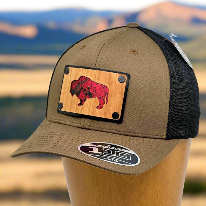 A brown and black hat with a wood and copper patch featuring a silhouette of a bison.