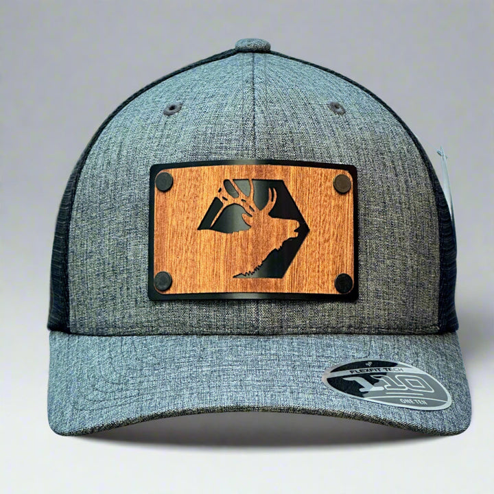 A grey and black trucker hat with a elk wood patch in mahogany.