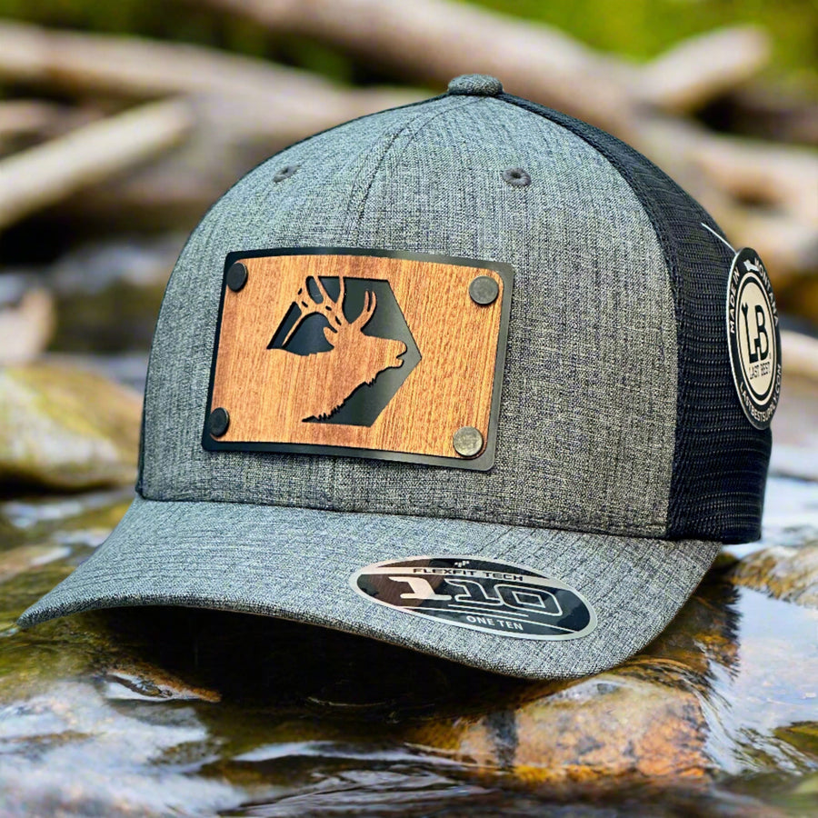 A grey and black trucker hat with a mahogany wood patch of an elk