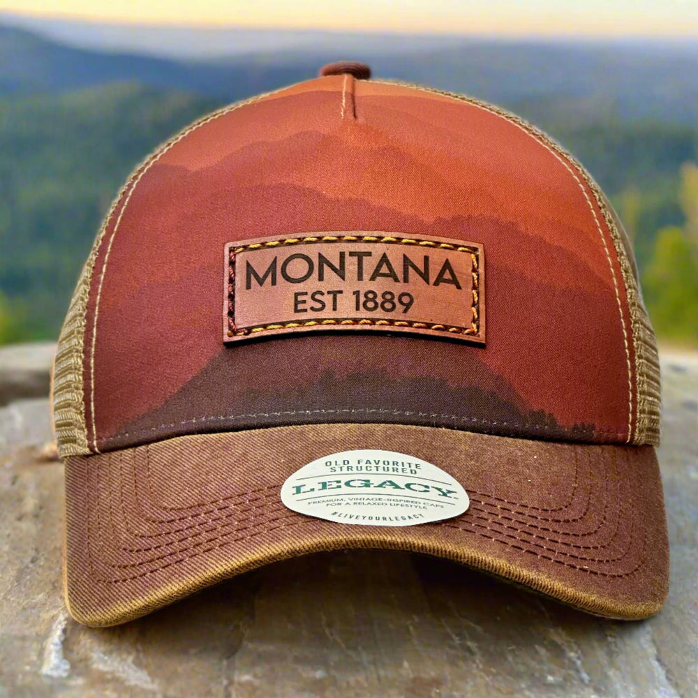 A Montana thick stitch leather patch on a trucker hat printed with mountains