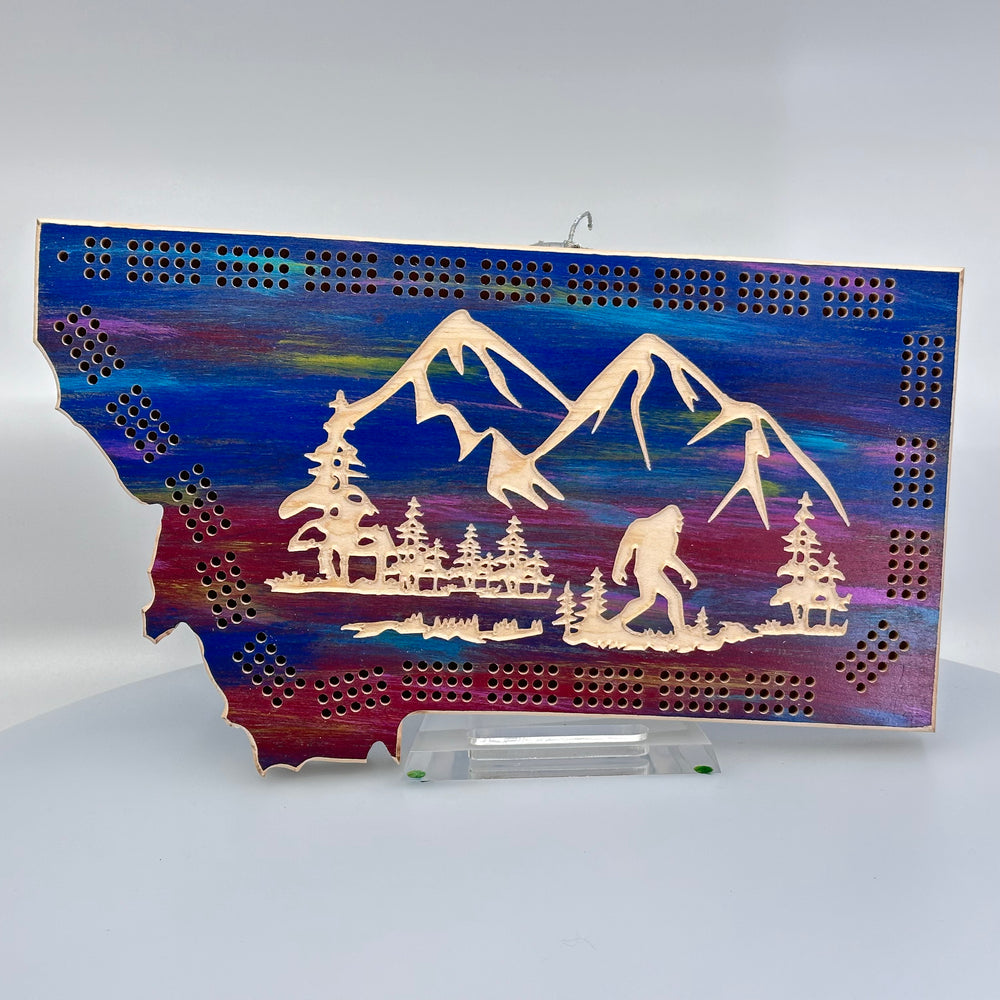 A made in Montana wooden cribbage board with an etching of Sasquatch and mountains.