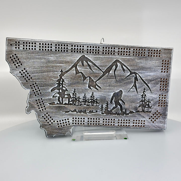 A made in Montana wooden cribbage board with an etching of Sasquatch and mountains.