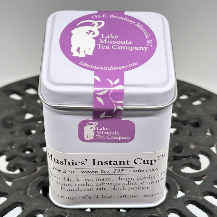 2.1 oz. tin of Lake Missoula Tea Company's Mushies' Instant Cup Tea--the perfect gift of Montana mushroom tea; image depicts the front and top of the tin