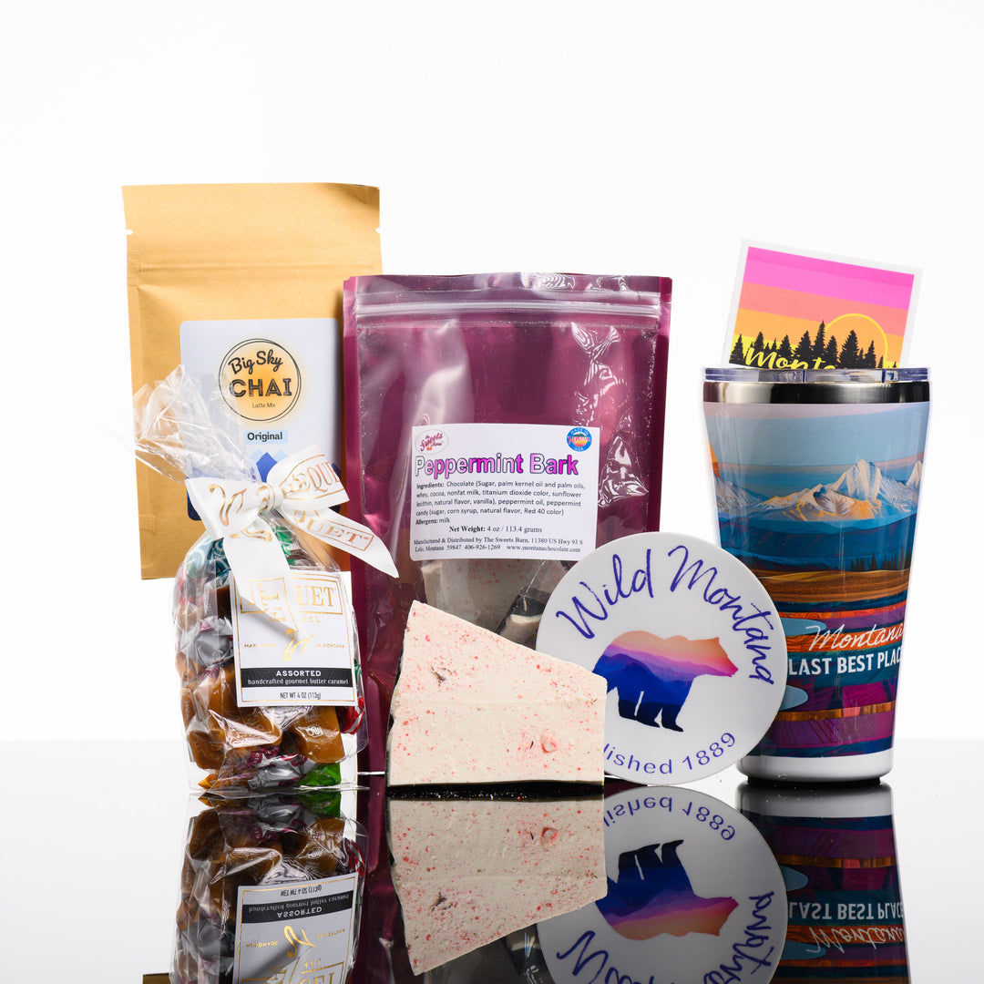 A picture of the Last Best Box, a Montana made gift box featuring Big Sky Chai, Peppermint Bark, Stickers, Bequet Caramel and a Montana scenery Tumbler.