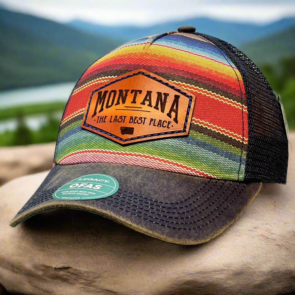 A poncho printed trucker hat with a thick leather patch that says Montana, The Last Best Place.