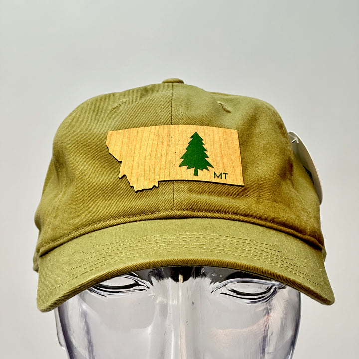 A made in Montana flexwood patch in the shape of Montana with an evergreen tree and the letters MT heat pressed onto an all cloth hat