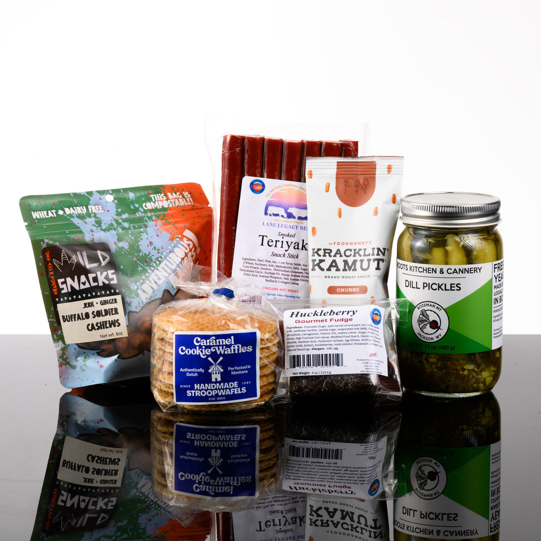 A Montana made snack gift box called The Last Best Box featuring teriyaki beef sticks, classic dill pickles, caramel cookie waffles, huckelberry fudge, buffalo soldier cashews and churro kracklin kamut.