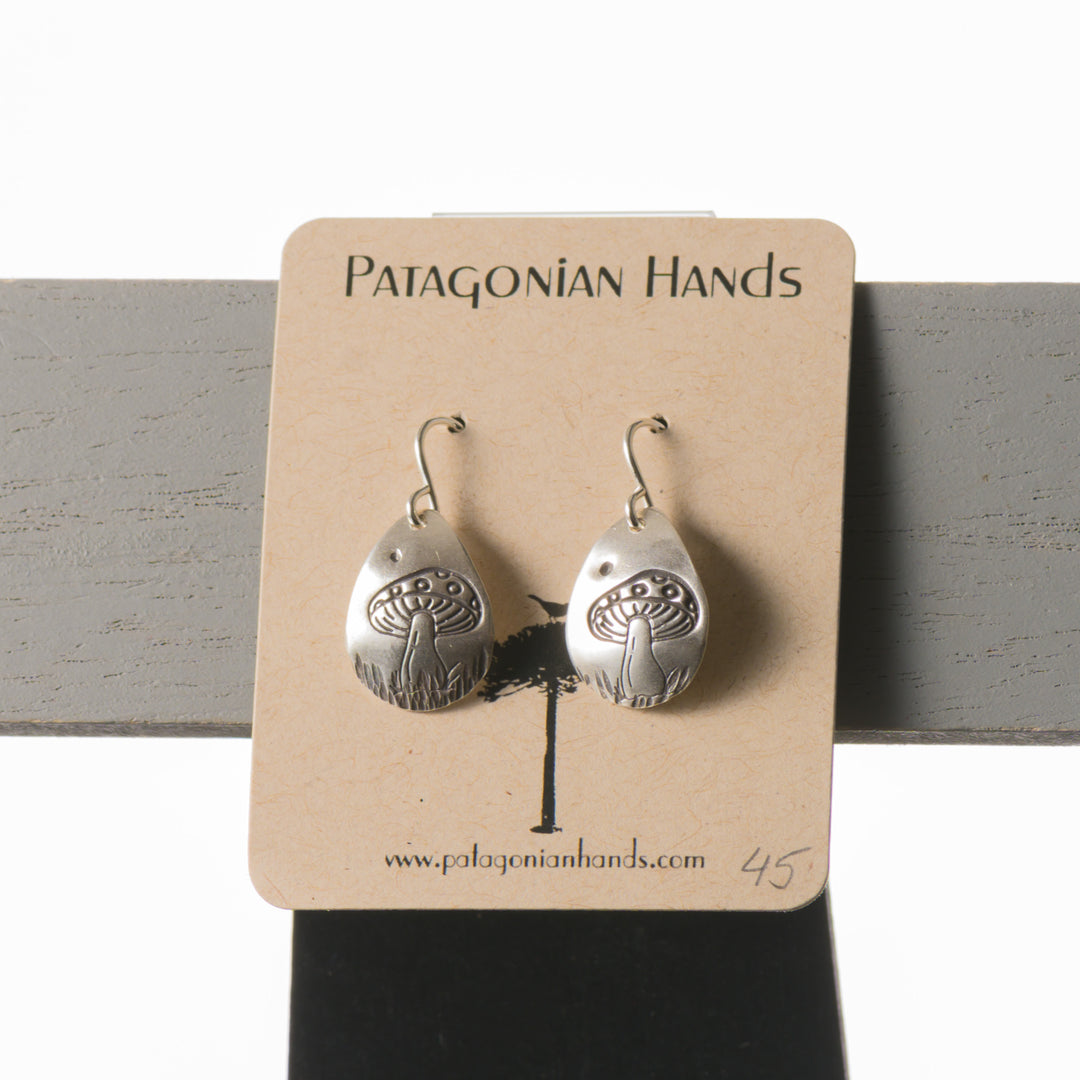 teardrop shaped handmade silver earrings with mushrooms stamped into them.