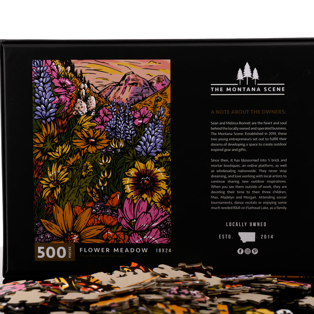 The front of a 500-piece Flower Meadow puzzle, made in Montana by The Montana Scene; image depicts the box back with puzzle pieces.