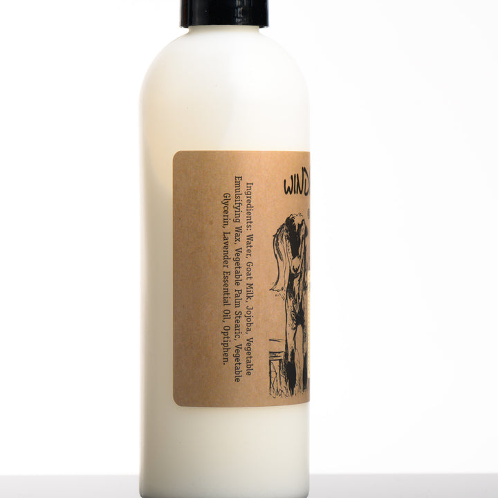 An 8 ounce bottle of Windrift Hill's made in Montana moisturizing goat milk lotion in scent lovely lavender showing the ingredients. Water, goat milk, Jojoba, vegetable emulsifying wax, vegetable palm stearic, vegetable glycerin, lavender essential oil, Optiphen