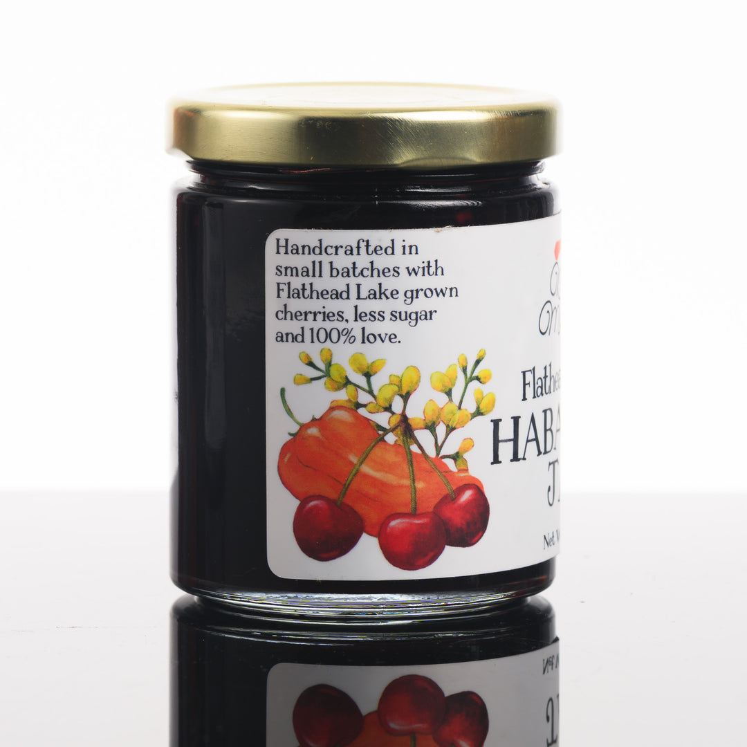 A picture of the side of a jar of flathead, cherry habanero jam that reads handcrafted in small batches with flathead Lake, grown cherries, less sugar, and 100% love