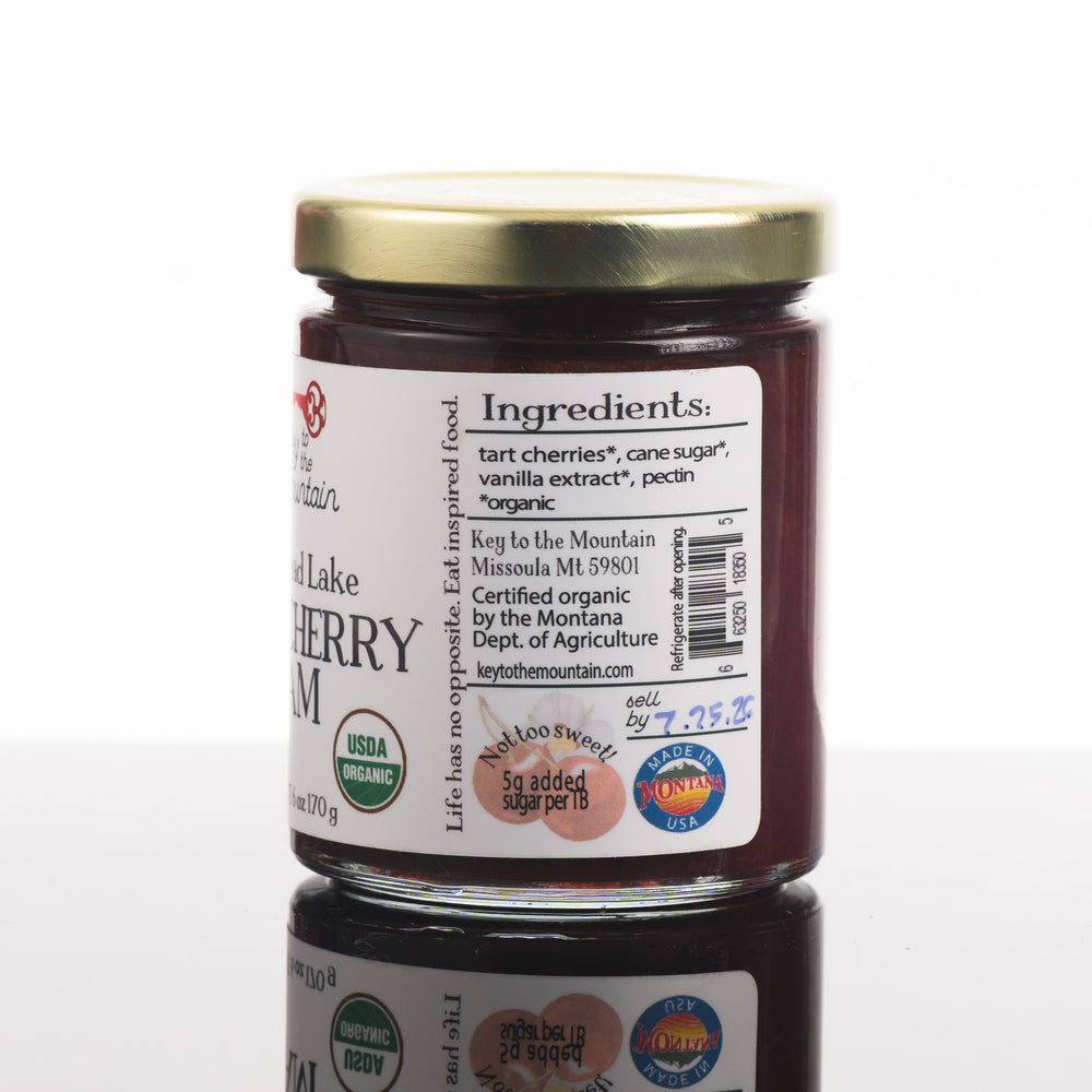 The side of a jar of flathead Lake tart, cherry jam, listing the ingredients. Organic tart cherries, organic cane sugar, organic vanilla extract, pectin.