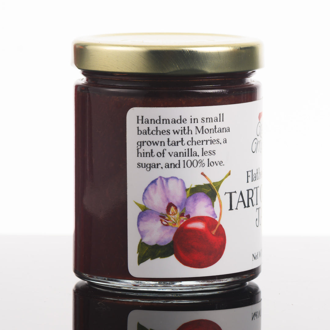 The side of a jar of Flathead Lake tart cherry jam that reads: Handmade in small batches with Montana grown tart cherries, a hint of vanilla, less sugar, and 100% love.