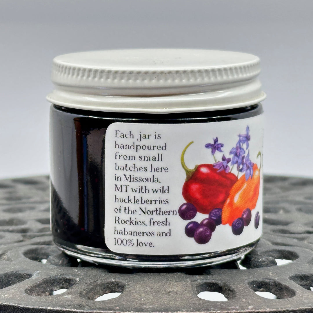 2 oz. jar of Key to the Mountain Huckleberry Habanero Jam, description reading each jar is hand poured from small batches here in Missoula, Montana with wild huckleberries of the northern Rockies fresh habaneros and 100% love.