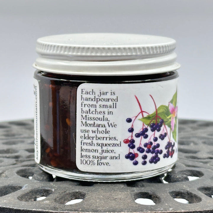 2 oz. jar of Key to the Mountain's Montana Grown Elderberry Jam, Side label text:  each jar is hand poured from small batches in Missoula Montana. We use whole elderberries, fresh squeezed lemon juice, less sugar and 100% love.