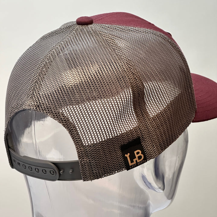 A back view of a made in Montana bear face cherry wood patch maroon and grey trucker hat.