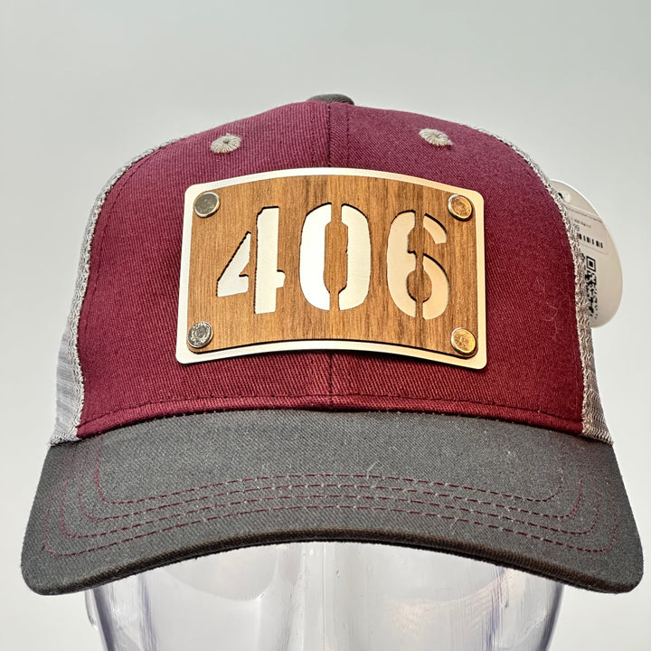 A  made in Montana 406 Walnut and metal patch riveted to a maroon and grey trucker hat.