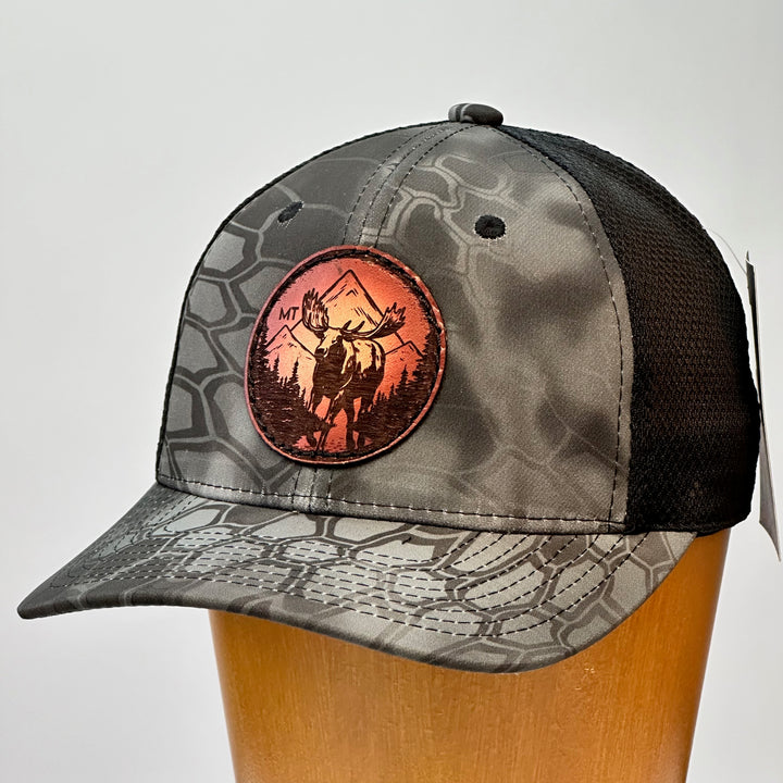 A made in Montana leather patch hat featuring a moose, sewn on a grey Kryptek trucker Hat.