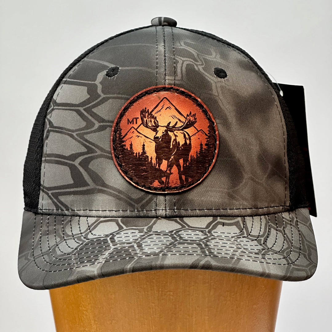 A made in Montana leather patch hat featuring a moose, sewn on a grey Kryptek trucker Hat.