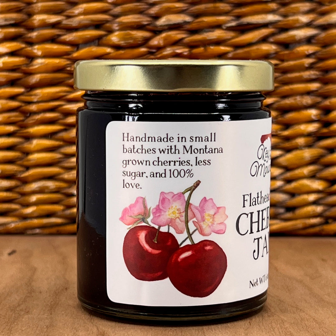 A 6oz jar of Key to the Mountain's handmade Montana flathead Lake Cherry jam reading handmade in small batches with Montana grown cherries, less sugar and 100% love.