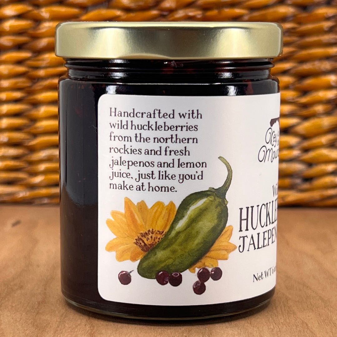 A 6oz jar of Key to the Mountain's Montana made Wild Huckleberry Jalepeno Jam Reading: handcrafted with wild huckleberries from the northern Rockies and fresh jalapeños and lemon juice just like you'd make it home.