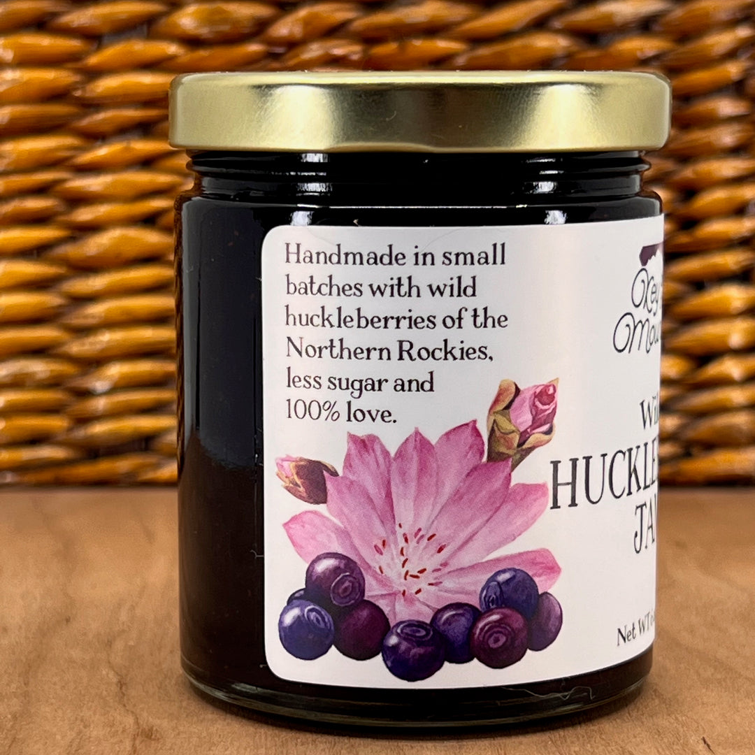 A 6oz jar of Key to the Mountain's, Montana handmade Wild Huckleberry Jam Reading handmade in small batches with wild huckleberries of the northern Rockies, less sugar and 100% love.