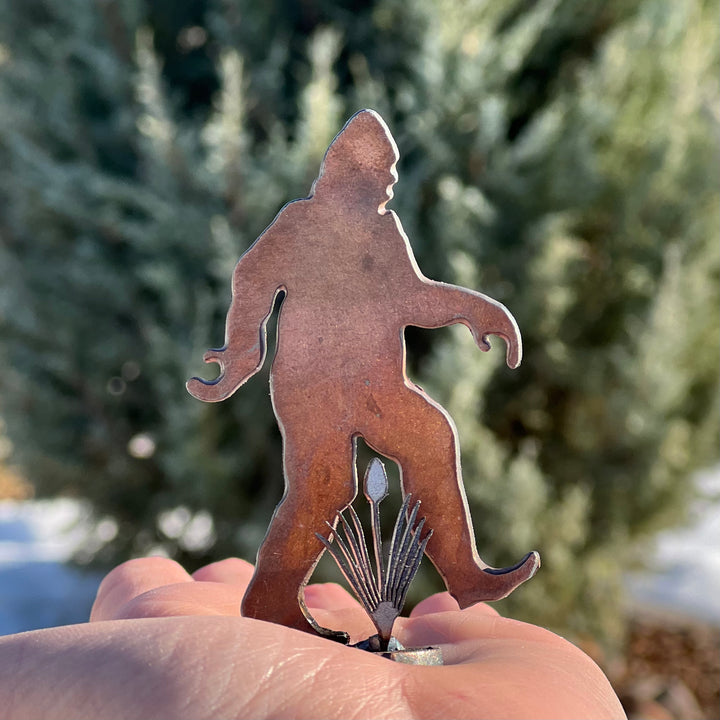 A picture of a mini bigfoot metal sculpture in the palm of a hand