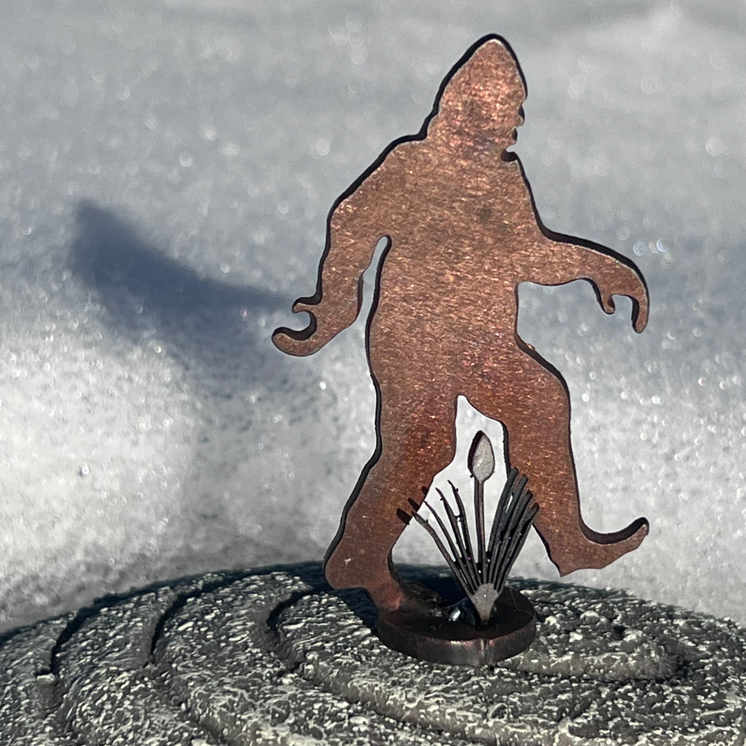 A mini sasquatch metal sculpture in the snow.